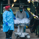 Kingsbrook Jewish Medical Center staff transport a deceased patient to a refrigerated truck on April 8, 2020 in Brooklyn.